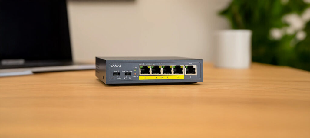 Switch PoE Cudy GS105P na biurku przy laptopie
