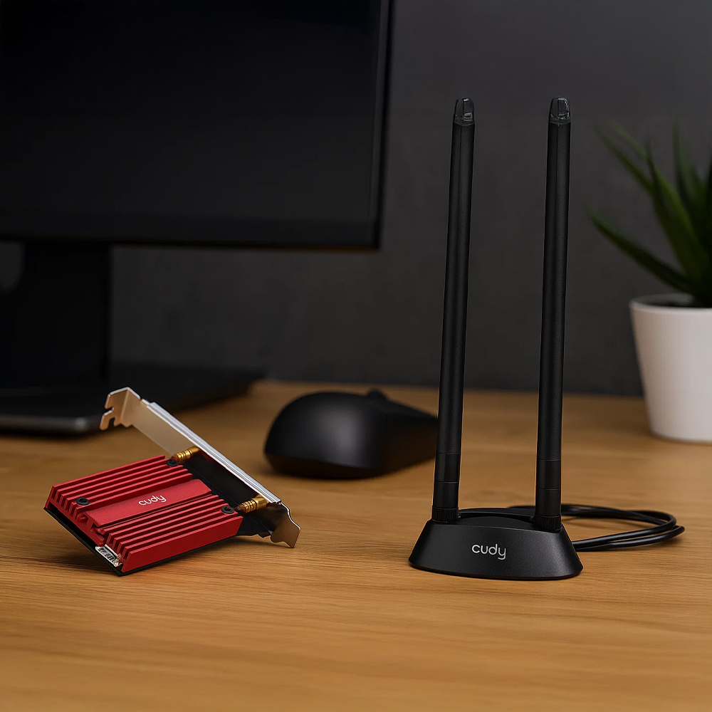 Adapter Wi-Fi 7 i Bluetooth Cudy WE9300S ustawiony na biurku przy komputerze Adapter Wi-Fi 7 i Bluetooth Cudy WE9300S położony przy komputerze